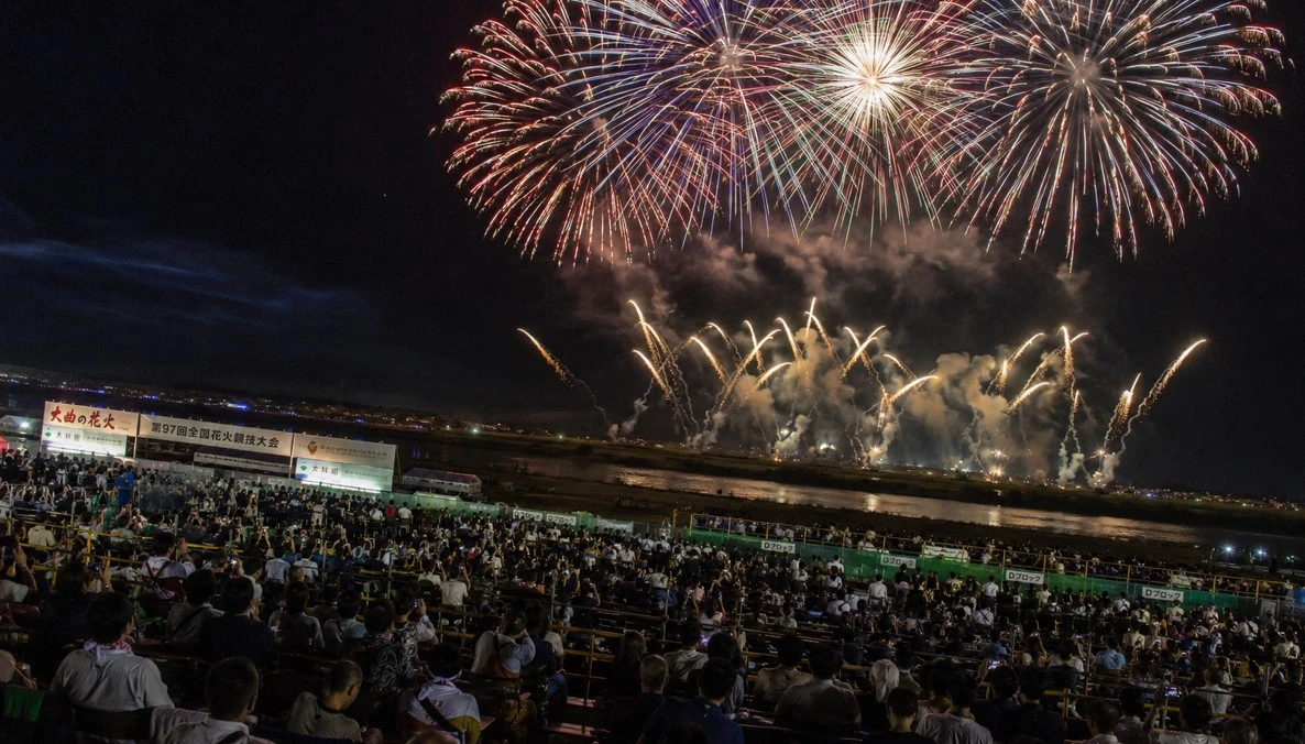 観覧席から大曲の花火を楽しむ多くの観客のイメージ