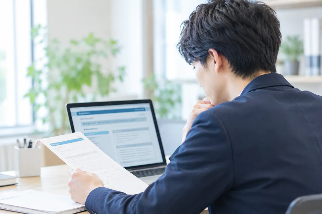 パソコンの前で申請書類を確認する男性