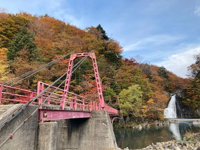 紅葉に囲まれた赤い吊り橋と法体の滝