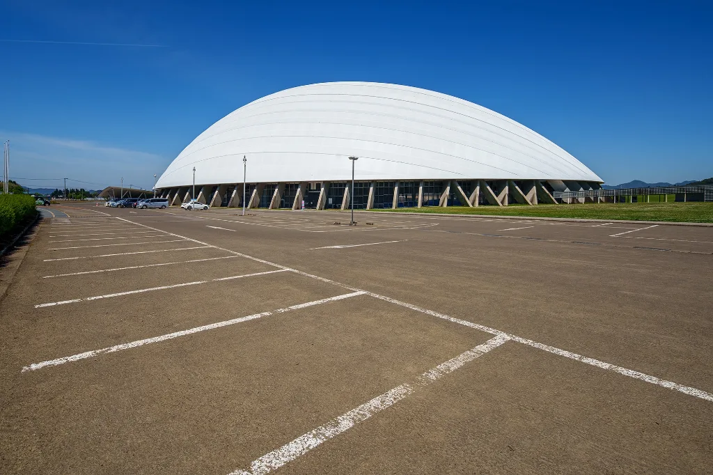 青空の下に建つニプロハチ公ドームと駐車場