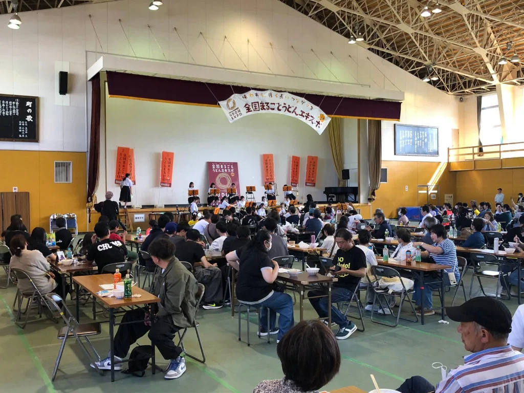 全国まるごとうどんエキスポの会場内でステージを囲んで食事をする来場者