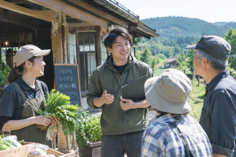地域おこし協力隊員と地域住民が農産物を手に交流している様子