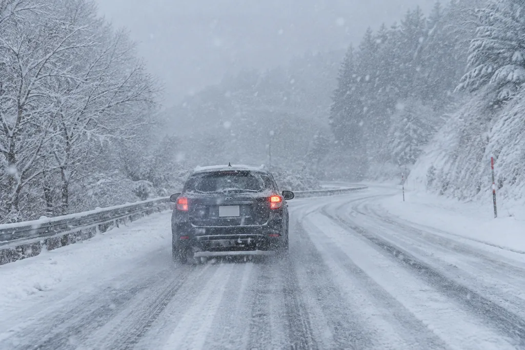 雪が降る秋田の道路を走る車