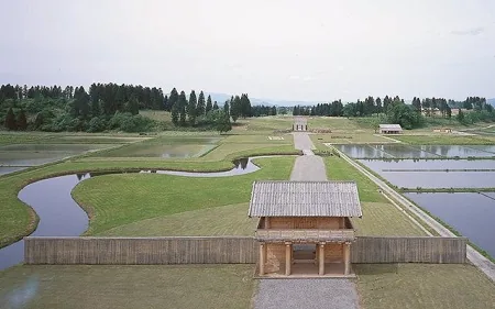 払田柵跡の木製案内板と芝生の広場の奥に建つ復元門