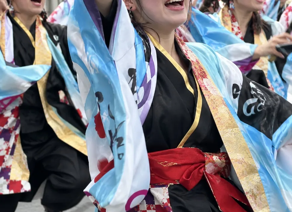 青と白の袖や赤い帯が特徴的な衣装で踊るよさこいの踊り手