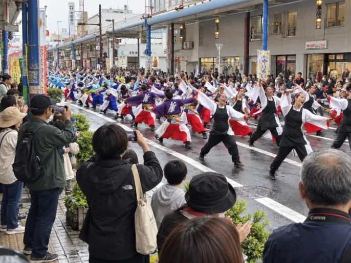 沿道の観客が見守る中、道路で一斉に踊るよさこいの参加者
