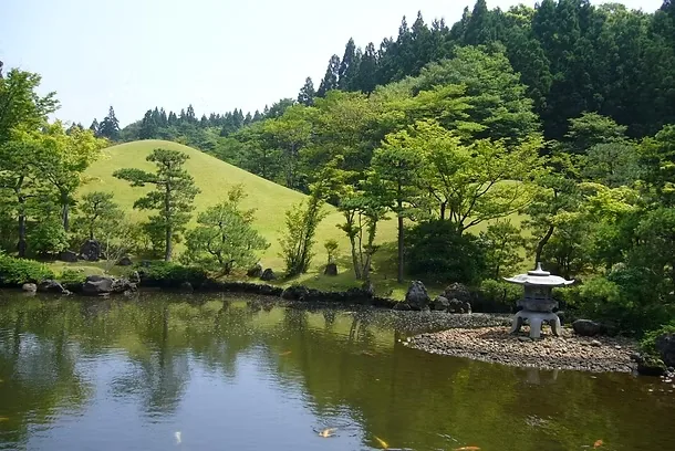 緑の木々に囲まれた池や築山が広がる夏の水心苑の日本庭園