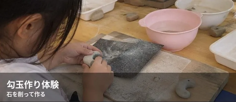弥生っこ村で石を削って勾玉を作る参加者